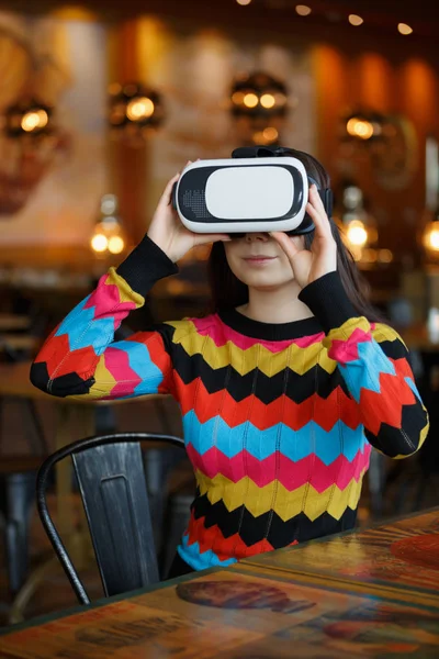 Vertical portrait of cute young white gamer girl playing mobile app game on smart phone with vr headset device.Portable modern virtual reality 3d glasses to play mobile application games everywhere