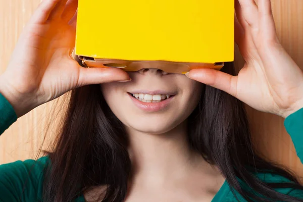 Cardboard gaming headset could be so much fun. This girl plays video game on her smart phone inside the box.