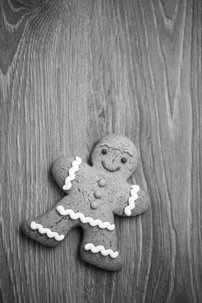Gingerbread cookie in shape of person lying on wooden table. Smiling eatable character with good taste. Close up macro, copy space on bright dark wood surface