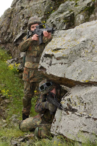 Military assistance.Army teamwork.Armed soldiers in camouflage of Ukrainian army in combat uniform.Soldier helps team member climb rock outdoor.War in Eastern Ukraine.Heavy ammunition,automatic rifle