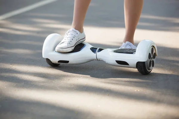 在公园的户外 女孩骑电动迷你悬停板滑板车的脚 利用电池供电的生态城市交通 不会对大气产生空气污染 — 图库照片