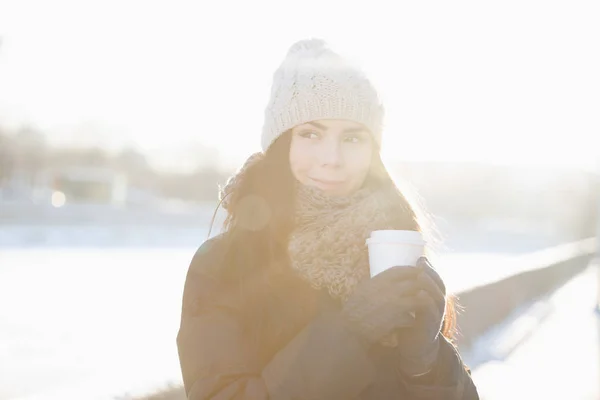 可爱的黑发小鸡享受热饮 从当地的咖啡师的白皮书外卖杯 将您的咖啡徽标放在干净的杯子上 以提供清凉饮料 镜头耀斑和明亮的阳光 模型在温暖的冬天穿戴 — 图库照片