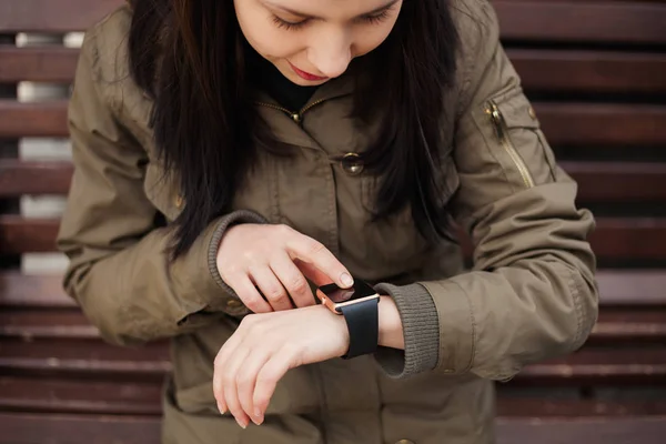 Smiling young girl using app on her trendy smart wrist watch. This person is always connected to social media and internet.
