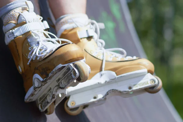 Legs of inline skater wearing professional aggressive rollerblades in a skatepark outdoors. Sitting on a ramp