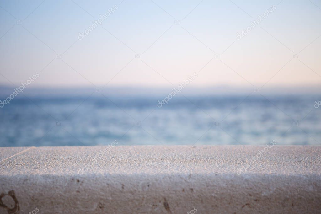 Beautiful background with blue sea water at sunset.Shallow depth of field,focus on stone surface to place product.Natural seascape view.Travel destination,simple backdrop