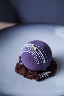 Güzel küçük yuvarlak tatlı pasta. Menekşe küresel kek krem tepesi ile. Dekoratif tatlı gıda pastane cafe tabakta servis. Kahve molası için fırın ürün. Öğle yemeği için tatlı yemek keyfini