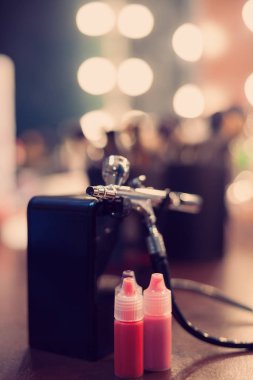 Boya bir stüdyoda bir profesyonel visagist tablo ile airbrush. Yeni teknoloji yüz makyaj ve cesedi sanata. Dikey yönlendirme. Modern hipster renkleri