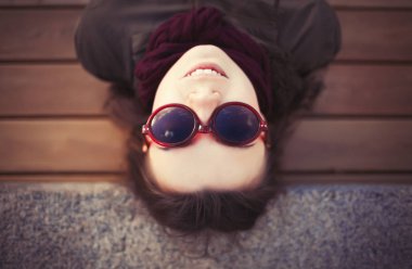 Pug burun gri parka ceket ve boş vakit açık havada bahar günü, güneş gözlüğü ile komik hippi kız. Sıcak film renk tonlarını.