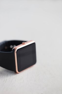 Beyaz ahşap zemin üzerinde modern akıllı saatler. Her zaman izin trendy yeni teknoloji internet ve sosyal medya ile bağlı kalın. Metin veya app simgesi boş siyah ekrana koyun. Makro yakın çekim