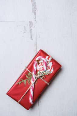 Güzel kırmızı Noel hediye kutusu ile sopa ve köknar ağacı dalı yalan beyaz ahşap yüzey üzerine. Düz lay ek yükü vurdu. Yakın çekim, hediye paketi üzerinde odak