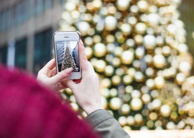 Noel ağacı açık havada genç esmer kız poz, açık renklerle dekore edilmiş