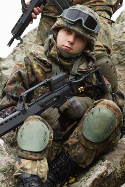 Askeri yardım. Ordu takım çalışması. Savaş üniforması içinde Ukraynalı ordunun kamuflajında silahlı askerler. Soldier takım üyesi tırmanmaya kaya açık yardımcı olur. Savaş Doğu Ukrayna. Heavy mühimmat, otomatik tüfek