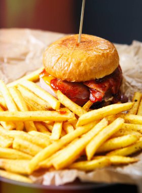 Lezzetli burger peynir ve ketçap dekoratif kahverengi kağıt fast food Restoran altın patates kızartması ile servis. Hamburgerin içine Cafe menü