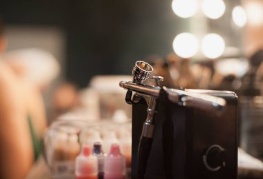 Airbrusher için profesyonel makyaj stüdyo daimi bir visagiste tablo. Kozmetik ve arka planda fırçalar.