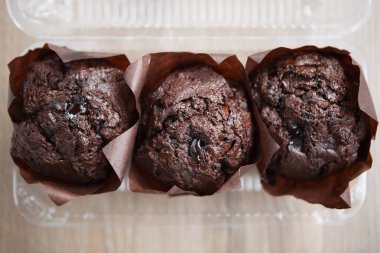 Kafede lezzetli çikolatalı kekler. Beyaz ahşap masa üzerinde dekoratif kağıt üç taze çikolatalı kek. Metni yerleştirmek için alanı kopyalama,odağı kapatma. 