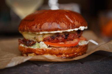 Lezzetli büyük taze hamburger ızgara sığır et, sebze ve et restoran rustik kağıt üzerinde hizmet sos ile. Fast food Cafe menü öğesi. Taze kaşarlı sandviç içinde kızarmış pirzola.