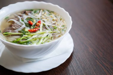 Asya Restaurant egzotik yemek keyfini çıkarın. Erişte ve sığır eti ile sıcak çorba kırmızı biber ve baharat ile servis. Vietnamca kafe yemek menü öğesi. Beyaz kase spiece ile doğal Çince yemek yemek