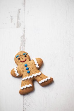 Komik gülümseyen zencefilli kurabiye adam ahşap masa üzerinde. İyi tadı ile gülümseyen yenilebilir karakter. Makro, parlak beyaz ahşap yüzey üzerinde kopya alanı kapatın