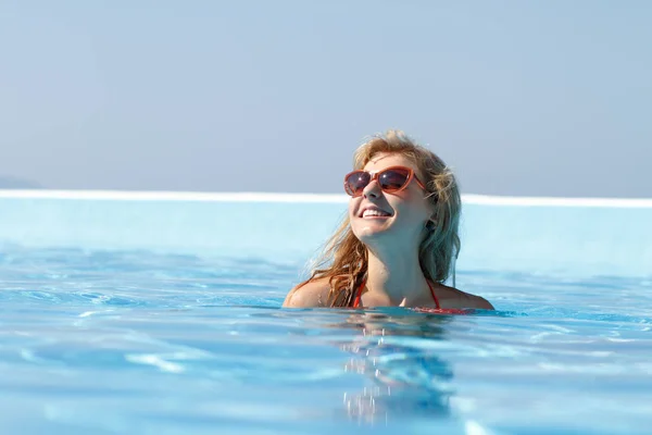 年轻漂亮金发碧眼的女人在游泳池里灿烂的夏日阳光下干净的蓝色酒店 快乐的表情 好寻找模型 — 图库照片