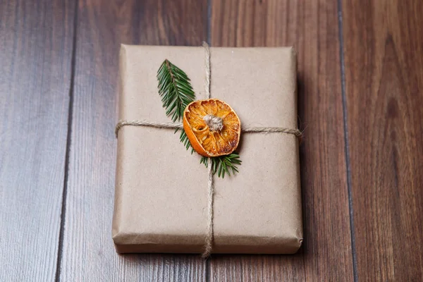 真棒手工制作质朴的圣诞礼品盒包 节日礼物包裹在装饰棕色的纸装饰与干橙片和冷杉树枝 平放置在木头背景 — 图库照片