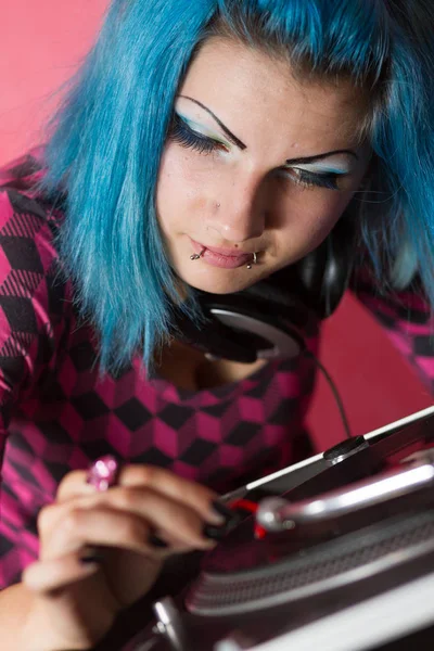 可爱的年轻女孩与蓝色染色的头发和粉红色的装备播放专业设备上的音乐记录 — 图库照片
