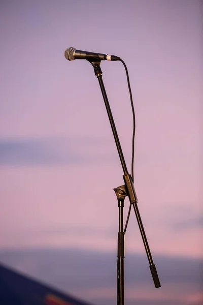 Professional vocal microphone on stand at summer music festival stage. Mic on the scene for singer