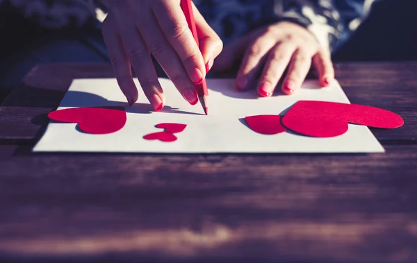 女の子は赤いハートで数字とホワイト ペーパーにラブレターを書きます 聖バレンタインの日コンセプト — ストック写真