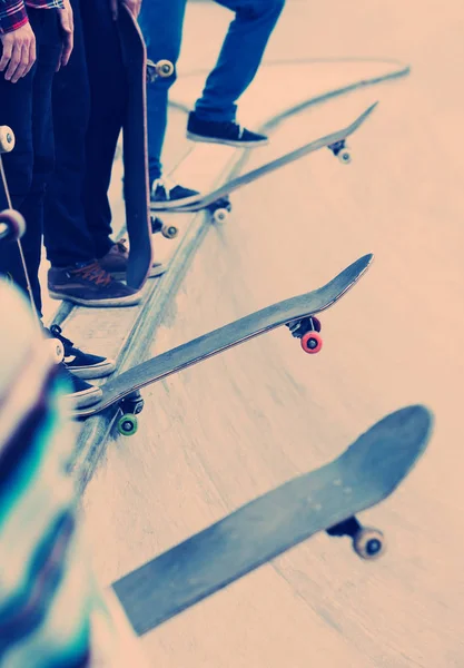 Skateboarders standing in a line on concrete ramp. Skateboarding contest or competition in outdoor skatepark. Dangerous extreme sport, popular among youth