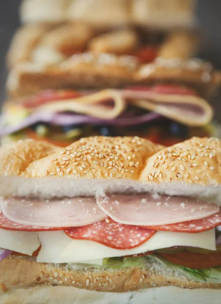 Tasty fresh sandwich in fast food restaurant menu.Delicious snack for lunch.Sliced ham & sausage,cut vegetables,sauce.Natural fastfood dish in cafe menu.Vertical food background