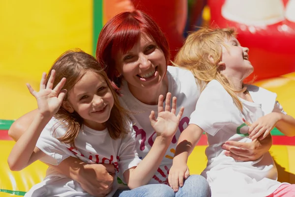 Jonge Moeder Met Haar Schattige Dochters Zwaaien Lachen Stuiterende Kasteel — Stockfoto