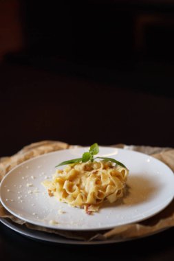 İtalyan makarna tabağı ve kekik yaprakları beyaz tabakta eritilmiş parmesan peyniri ile servis ediliyor. Restoranda nefis İtalyan mutfağı. Lezzetli ve doğal yemek.