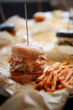 Fast food Cafe menüsünde plaka üzerinde dikey atış büyük lezzetli burger Kızarmış havuç dilimleri ile servis. Abur cubur Restoran tabak kapatın. Büyük soslu pirzola kavrulmuş ve peynir dilim yandı