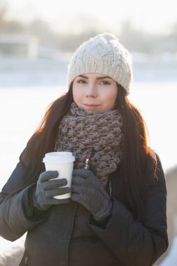 Sevimli genç beyaz kadın Buharlaştırıcı ecig ve sıcak kağıt kapuçino kupa tutun. Çok kadın modeli giymek sıcak kış giysileri içinde soğuk parlak gün açık. Sigarayı bırakmak, vaping başlamak