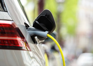 Elektrikli otomobil park pille sarı kablo ile şarj moden. Aracınızın yeni binmek için elektrik enerjisi ile şarj edin. Hava kirliliği ile ekolojik şehir ulaşım 