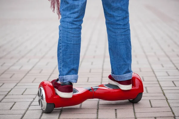 一个女孩骑在现代红色电动迷你赛格威或悬停板滑板车的脚 不断推出新的运输技术 它非常有趣 很容易骑行 不会对大气产生空气污染 在模型腿和小工具上关闭 — 图库照片