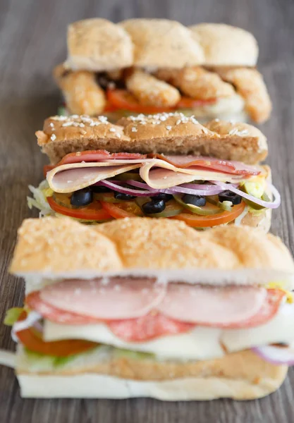 Fresh sandwiches with tomato,ham & parmesan cheese slice,black olives & mustard sauce on table in cafe. Fast food restaurant menu close up. Delicious street food dish.