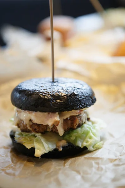 Big tasty black burger in fast food restaurant menu .Delicious sauce & green lettuce salad leaves in crusty bun. Grilled beef meat peace.Fat junk food in American cafe menu