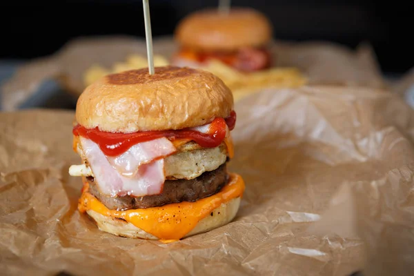 Delicious big fat crafted hamburger with bacon slice,ketchup & smoked cheese served on paper plate in fast food restaurant menu.Junk food dish in cafe close up.American burgers