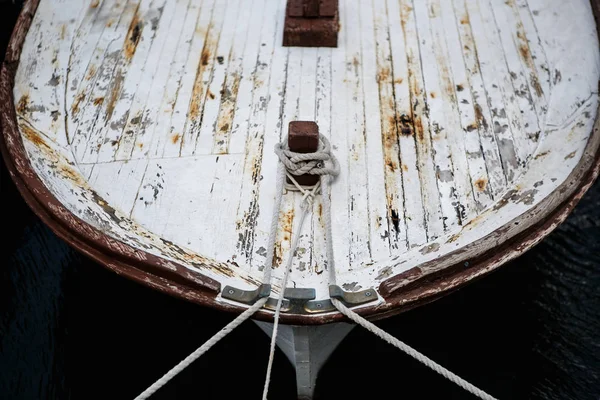 Old motor boat tied with knots to the pier.Vintage watercraft drfits on water in harbor of Makarska city in Croatia.Retro yacht parked in haven.Rusted old boat