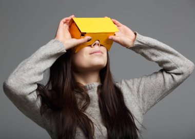 Mobil oyun uygulaması sanal gerçeklik kulaklık aygıtta oynayan genç kız. Mobil oyun için sarı kart tahta kutu. Taşınabilir vr baş teknoloji oyuncular için ayarlayın. Artırılmış gerçeklik gadget Moblie oyunları oynamak için