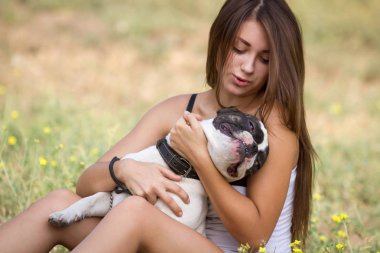genç esmer kız parkta onun sağlıklı genç bulldog ile oynarken
