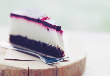 Lezzetli ahududu peynir pastasından bir tahta üzerinde geç bir kafede çatal ile görev yaptı. Lezzetli pasta - krem, çilek ve taze bisküvi. Makro fotoğraf kadar kapatın.