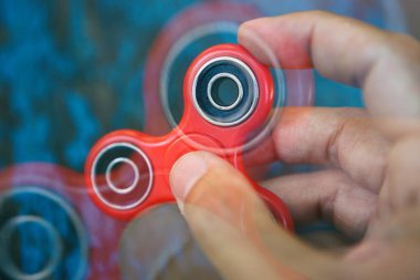 Süper popüler kırmızı spinner aygıt erkek elinde. Topluca Gadget'ı elinde tutan adam. Modern dönen gençler ve yetişkinler için bir oyuncak. Serin yeni hileci öğrenmek ve eğlenmek. Kırmızı nesne, mavi arka plan