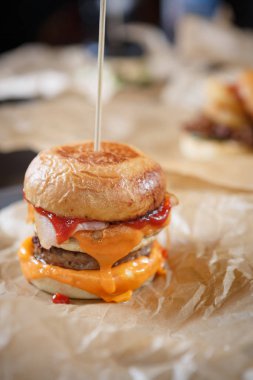 Lezzetli büyük şişman hazırlanmış hamburger pastırma dilimi, ketçap ve füme peynir ile fast food restoran menüsünde kağıt tabakta servis. Abur cubur yemek kafede kapatın. Amerikan Burger