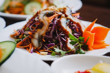 Egzotik yılan balığı salata kırmızı lahana ve taze sebze ile Asya kafede beyaz tabakta servis. Vietnam restoranı gurme yemek. Akşam yemeği ya da öğle yemeği için lezzetli renkli yemek