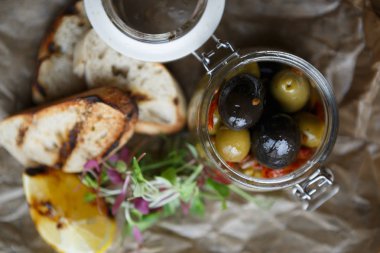 Cam kavanozda taze yeşil ve siyah Yunan zeytinleri. Restoranda lezzetli meze. Egzotik kanape Tepesi. Zeytin sebzeleri yakın. Gurme gıda menü öğesi