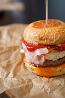 Fast food restoran dekoratif kahverengi kağıt üzerinde büyük şişman hamburger sığır eti ve sos ile servis. Kafe menüde lezzetli bir yağ abur cubur sağlıksız satın. Sigara içen domuz eti taze topuz