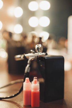 Boya bir stüdyoda bir profesyonel visagist tablo ile airbrush. Yeni teknoloji yüz makyaj ve cesedi sanata. Dikey yönlendirme. Solma film renkleri