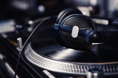 DJ heaphones vinl kayıt üzerinde. Kayıt oyuncu döner. Büyük siyah kafa telefonları odak. Müzik dinlemek, ev partisi parçaları çalmak. Ses cihazı