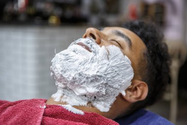 Genç siyah ile beyaz tıraş kremi berber dükkanı yüzünde. Tıraş köpüğü salonda Afrika adamla. Erkek güzellik tedavi kavramı